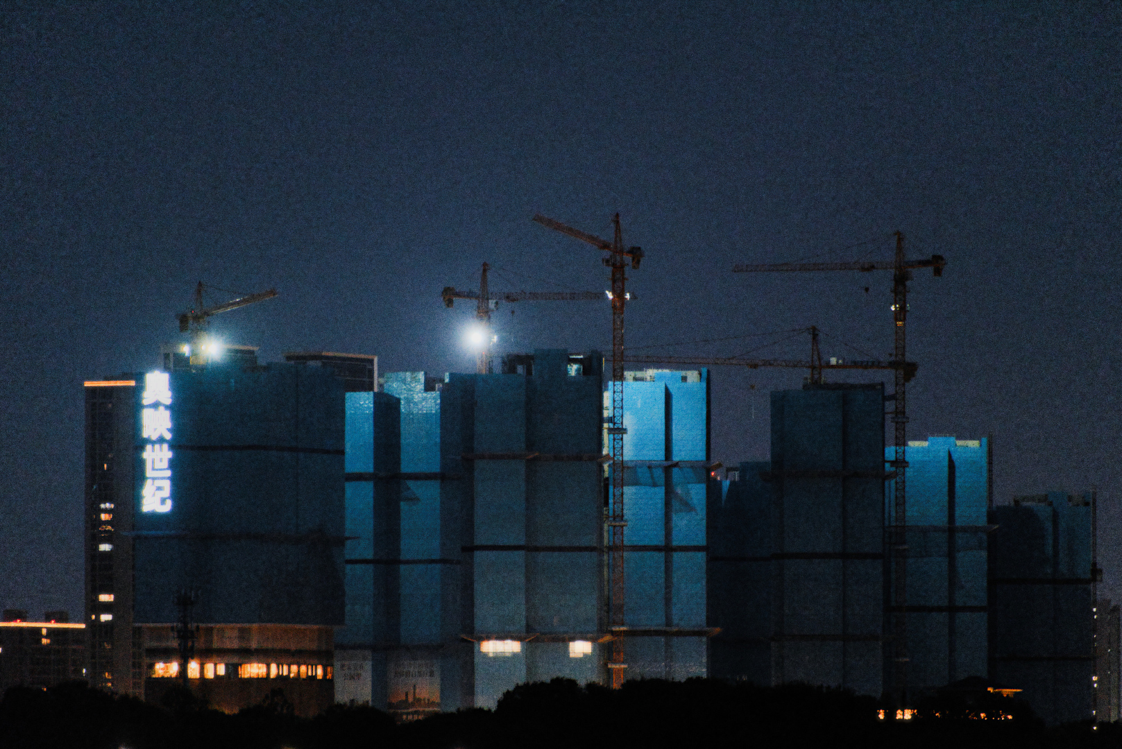 A group of buildings under construction at night covered in blue