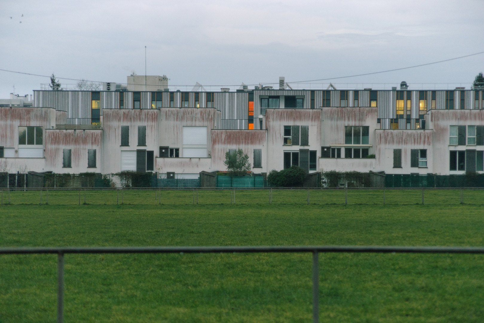 Modern housing with illuminated windows under an overcast evening sky