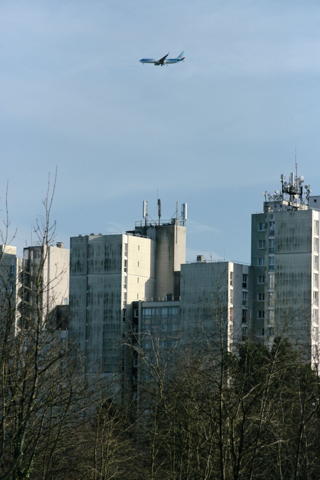 A plane flying over tall buildings in Bures-sur-Yvette